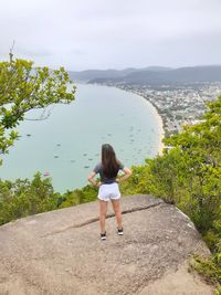 Rear view of woman standing by plants against sky