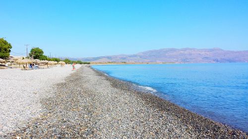 Scenic view of beach against clear blue sky