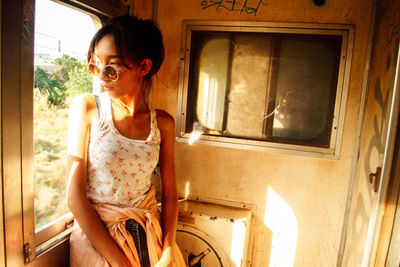 Portrait of a smiling young woman standing against window