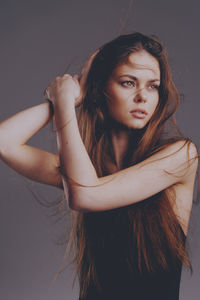 Portrait of young woman looking away against wall