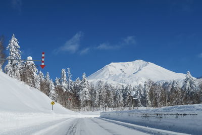 Snow covered road by snowcapped mountain against sky