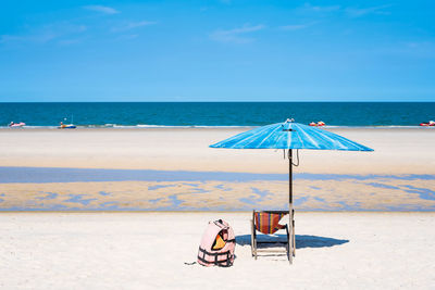 Deck chairs on beach against sky