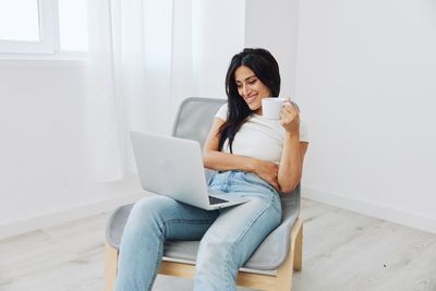 Young woman using laptop while sitting on sofa at home