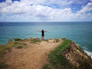 Woman standing at beach against sky