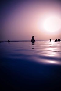 Silhouette people standing on beach against clear sky during sunset