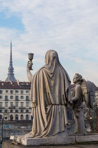 Statue in front of buildings at piazza vittorio veneto against sky