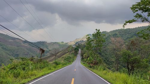 Road amidst trees against sky