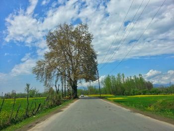 Road amidst field against sky