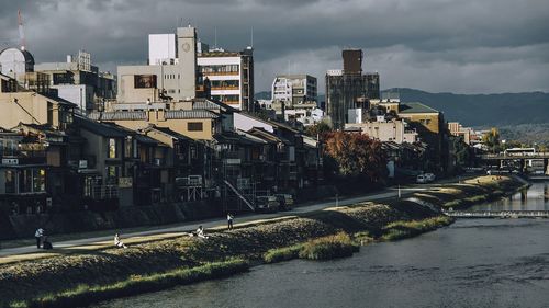 Buildings by river against sky in city