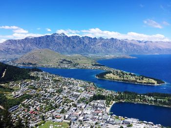 Aerial view of sea and mountains against blue sky