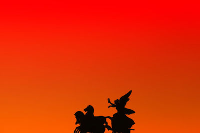 Silhouette people standing against orange sky