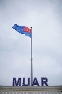 Low angle view of flag flags against sky