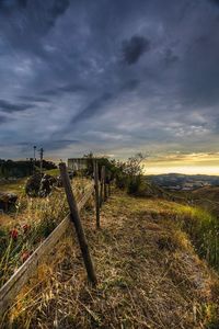 Fence on beach against cloudy sky