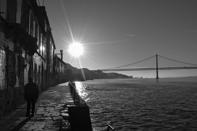 Rear view of man on bridge over sea against sky