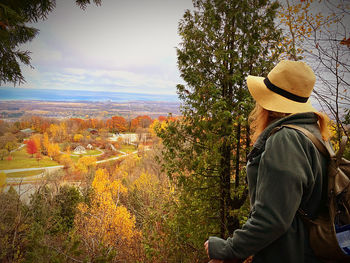 Rear view of person standing by tree against sky