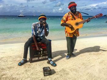 Full length of men playing on beach against sky