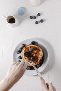 A woman is taking a slice of a stack of pancakes