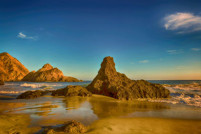 Scenic view of sea and mountains against blue sky