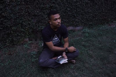 High angle view of young man looking away while sitting on land