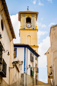 Low angle view of clock tower amidst buildings against sky