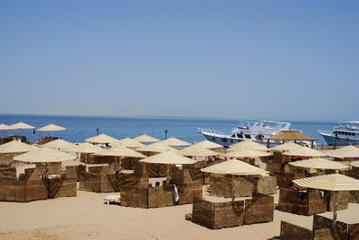 Parasols with chairs at beach against clear blue sky