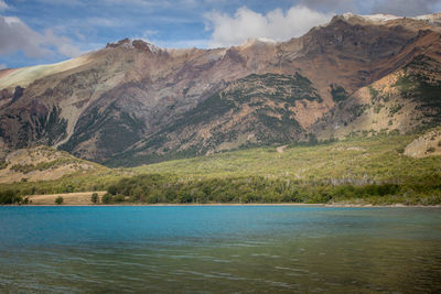 Scenic view of lake by mountains against sky