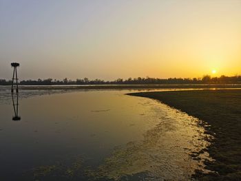 Scenic view of lake against clear sky during sunset