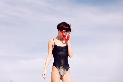 Young woman standing against sky