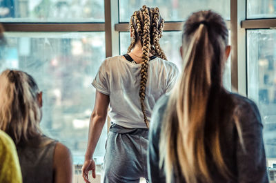 Rear view of women standing against window