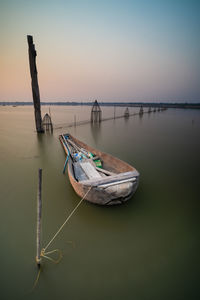 Boats moored in sea against sky during sunset