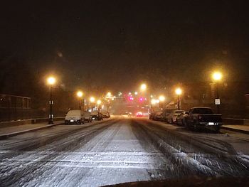 Road passing through illuminated city at night