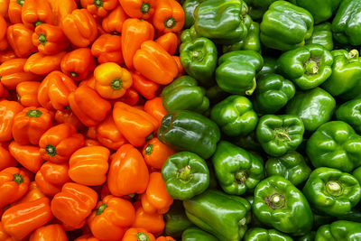 Bright orange and green bell peppers, contrasting in color but similar in shape,