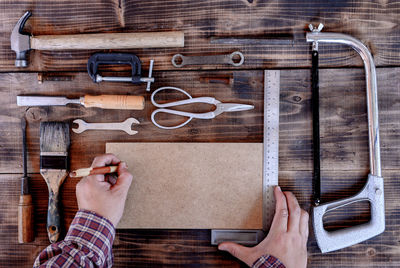 Cropped hands of worker with work tools on table