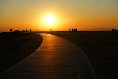 Silhouette people on beach against sky during sunset