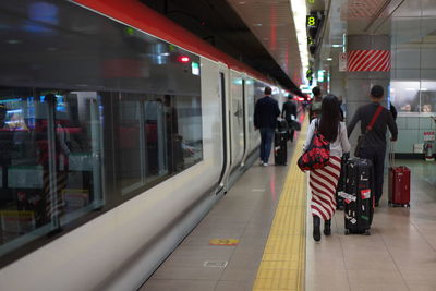 Rear view of people waiting at railroad station