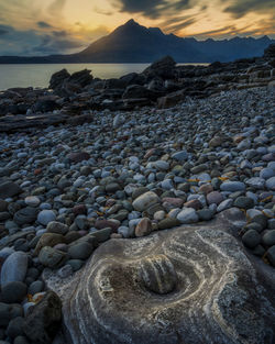 Rocks on beach against sky during sunset