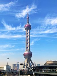 Communications tower in city against sky