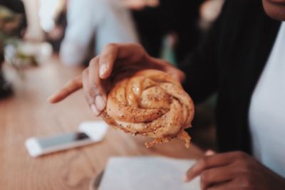 Midsection of woman holding croissant at table