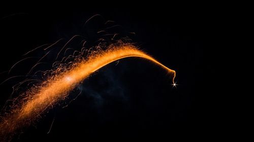 Low angle view of illuminated fireworks against black background