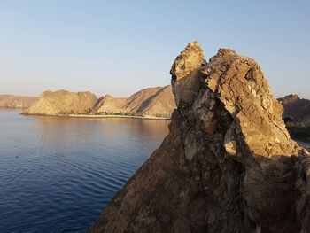 Rock formations at beach against sky