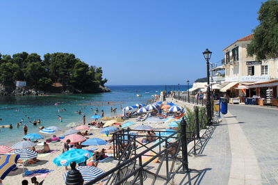 People on beach against clear blue sky