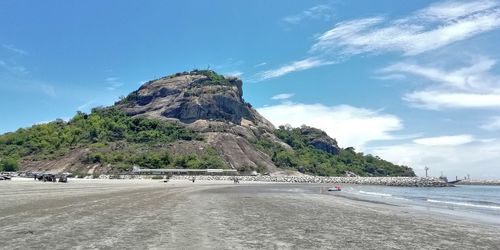 Scenic view of sea by mountain against sky