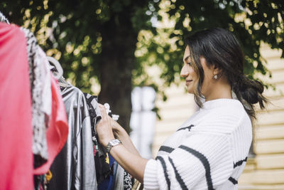 Low angle side view of smiling woman buying dress at flea market