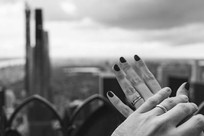 Close-up of person holding hands against sky