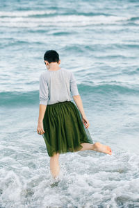 Rear view of woman standing at beach