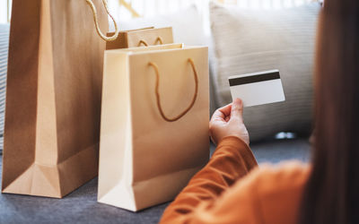 Closeup image of a woman holding credit card with shopping bags at home for online shopping concept