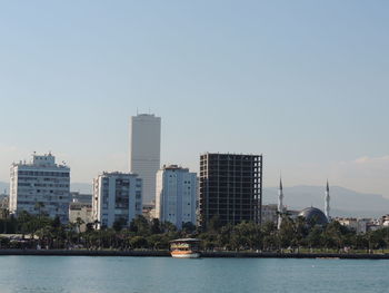 Buildings by river against sky in city