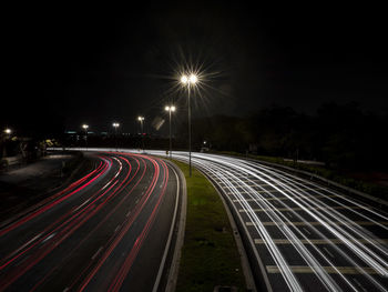 Light trails on road against sky at night