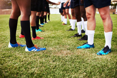 Low section of people playing soccer on field