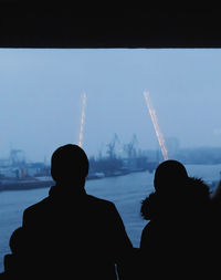 Rear view of silhouette people against sky in city